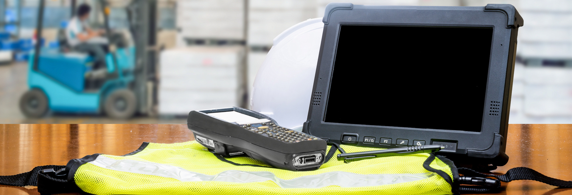 Rugged computers tablet and Bluetooth barcode scanner in front of modern warehouse